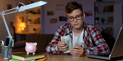 teenage boy counting cash at his desk